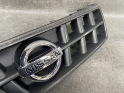 Close-up of a Nissan grille featuring the chrome Nissan emblem