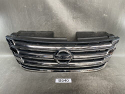 Front grille of a Nissan vehicle with chrome horizontal bars and circular Nissan emblem in the center