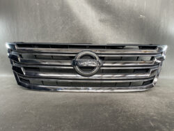 Front grille of a Nissan car with chrome horizontal bars and the circular Nissan emblem in the center.