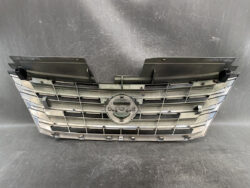 Front grille assembly from a car, featuring horizontal chrome slats and a central circular emblem mount area.