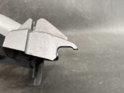 Close-up of a silver metal cutting blade with a curved hooked end attached to a plastic tool base.