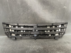 Black car front grille assembly with mounting tabs laid on a work surface