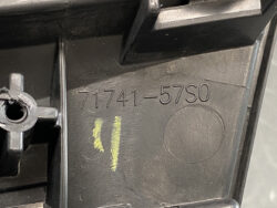 Close-up of a black plastic automotive part stamped with the part number 71741-57S0 and two yellow paint marks nearby, plus a circular molded impression.