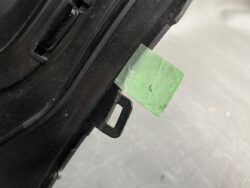 Green sticky-green tape attached to the side of a black plastic component, suggesting labeling or marking nearby edge.