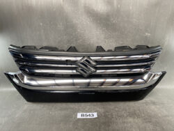 Front grille and lower bumper of a Suzuki car with chrome horizontal bars and a centered emblem.