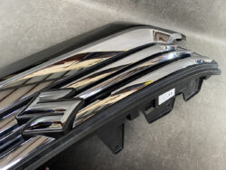 Close-up of a chrome Suzuki emblem on a glossy front grille of a vehicle.