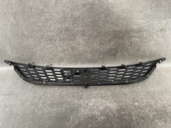 Black front grille with diamond-like mesh and multiple mounting tabs for installation on a vehicle chassis, shown lying on a surface.