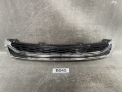 Front bumper grille assembly with a black honeycomb center and chrome trim, laid on a gray workshop surface.