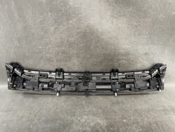 Rear bumper cover interior showing mounting clips and attachment points on a black plastic panel on a gray surface.