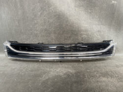 Front grille of a car with a black honeycomb pattern and chrome trim, placed on a gray surface.