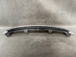 Curved plastic car bumper cover with three mounting clips on a dark surface.