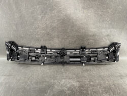 Plastic car bumper inner panel with mounting clips on a gray surface (informative component).