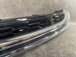 Close-up of a dark car grille with a hexagonal honeycomb pattern and a chrome bumper beneath it.
