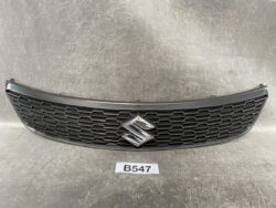Grille from a Suzuki vehicle with a black honeycomb pattern and a chrome Suzuki emblem in the center (curved bumper-to-bumper design).