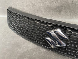 Close-up of a black car grille with a chrome Suzuki emblem in the center