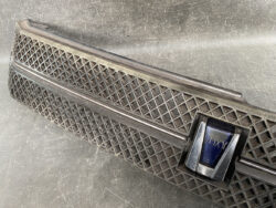Long black car grille trim with a diamond lattice pattern and a blue Vox emblem