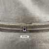Front view of a car grille with diamond-pattern mesh and a central blue emblem on a grey surface