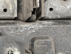 Close-up of a dusty black automotive plastic cover with stamped part numbers and an 'A1' marking visible.