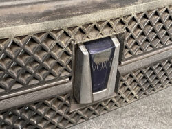 Close-up of a dusty car grille featuring a blue VOXAN emblem in the center.