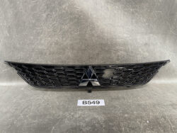 Front grille of a Mitsubishi vehicle with a black honeycomb pattern and centered emblem in the middle of the grille.