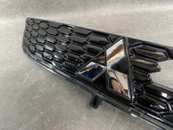 Close-up of a glossy black car grille with a chrome Mitsubishi emblem in the center.