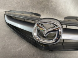 Mazda emblem centered on a front grille, chrome ring around the logo.