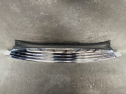 Chrome bumper molding with black rubber mounting strip laid on a gray surface.