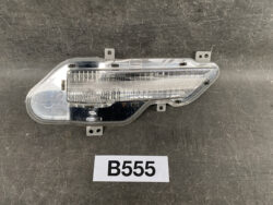Clear car taillight assembly with LED strip and mounting tabs on a dark surface.