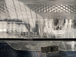 Close-up of a chrome metal plate with stamped markings including 'JAPAN' and numbers, and a small dark textured patch at the bottom.