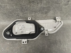 Rear car tail light housing with mounting brackets and gasket, shown from above on a dark surface
