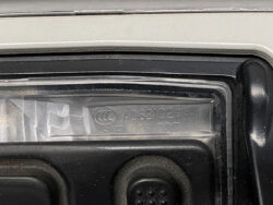 Close-up of a black plastic latch area with engraved numbers and a circular emblem in the molded clear plastic plate inside a device component.