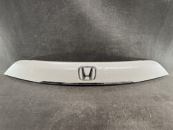 White car trunk trim panel with a centered chrome Honda emblem and a thin chrome accent strip