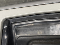 Close-up of a car door frame and window seal with embossed serial numbers on the plastic trim.