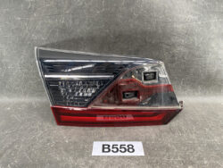 Tail light assembly with clear upper lens and red lower reflector on a grey surface. Two square reverse-light openings visible in the red section.