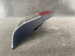 Blue curved handheld light with a red translucent lens on top, resting on a scratched gray surface.