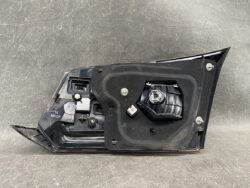 Automotive tail light assembly viewed from the back, showing bulb socket and mounting plate