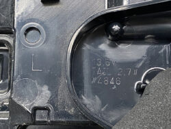 Close-up of a dark plastic car component with a circular port and the molded text: '13.5V TAIL 2.7W W4846' and an 'L' marker nearby.