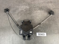 Black car seat adjustment module with cables and mounting brackets on a workshop floor; label B563 nearby.