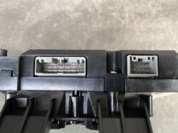 Two gray rectangular electrical connectors with exposed metal pins on a black plastic module, viewed from above.