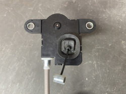 Black plastic sensor/actuator housing with two side mounting lugs and a central sensing area, connected to a brown cable at the bottom.