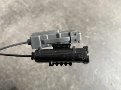 Suzuki Solio Mitsubishi Delica D:2 Genuine Power Slide Door Motor 79R0L Left Side 18 Close-up of a small gray plastic block attached to a black housing, with a gray cable entering from the left and a toothed edge below.