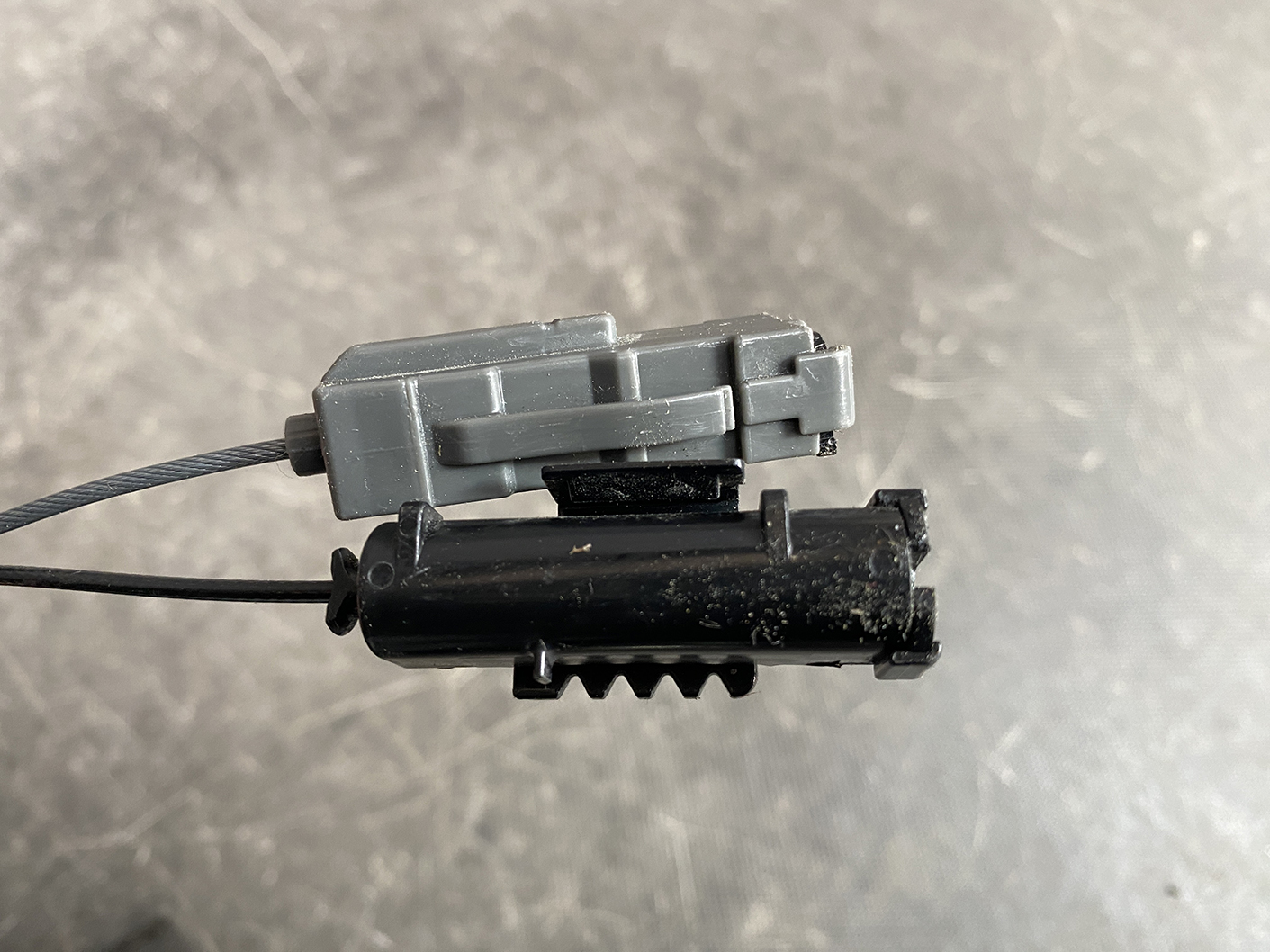 Suzuki Solio Mitsubishi Delica D:2 Genuine Power Slide Door Motor 79R0L Left Side 9 Close-up of a small gray plastic block attached to a black housing, with a gray cable entering from the left and a toothed edge below.
