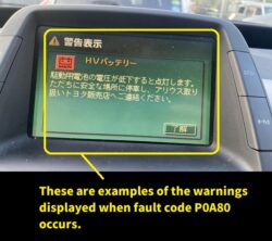 In-car diagnostic display with a yellow border showing an HV battery low voltage warning in Japanese and acknowledge button.